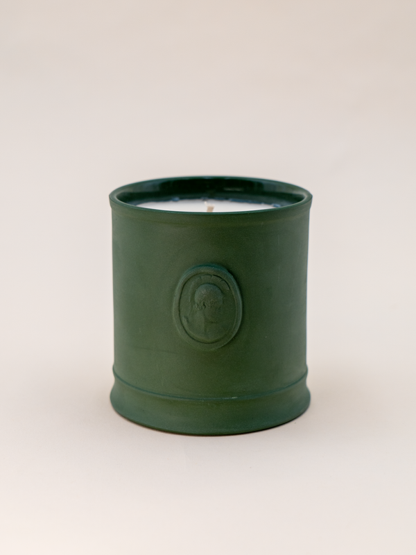 Green candle in a decorative container on a white background